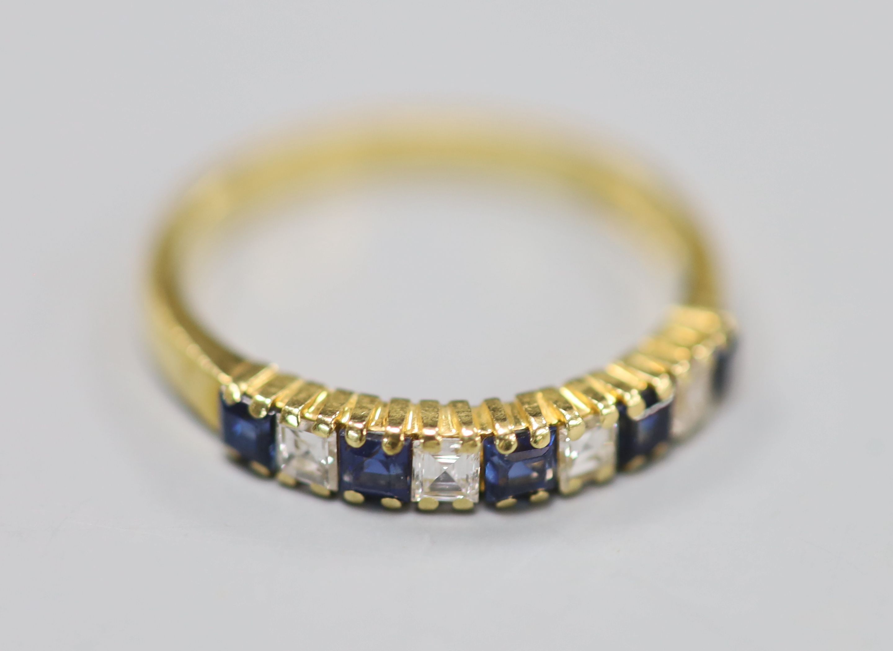 A modern 18ct gold, five stone sapphire and four stone diamond set half hoop ring, size M/N, gross 3.1 grams.